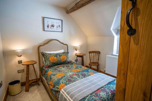 a bedroom with a bed and two chairs and a window at March Hare Cottage in Bretforton in Bretforton