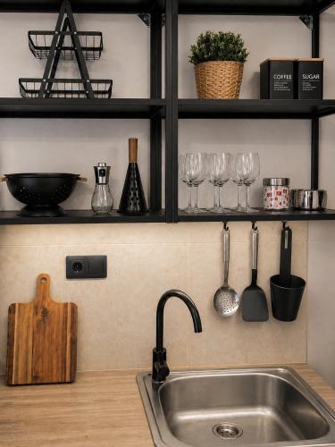 a kitchen with a sink and wine glasses on shelves at Cocomelo apts 3 luxury in Heraklio