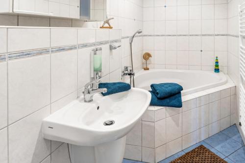 a white bathroom with a sink and a bath tub at Ferienwohnung Auszeit in Berlin