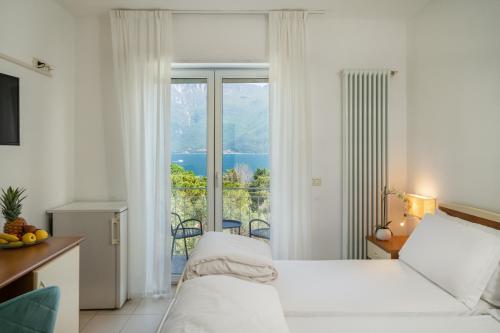 a bedroom with a bed and a large window at Hotel Casa Piantoni in Limone sul Garda