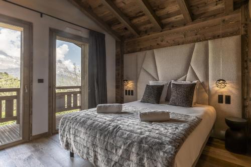 a bedroom with a large bed and a large window at Chalet Suzane - Panorama Mont-Blanc & jacuzzi in Combloux
