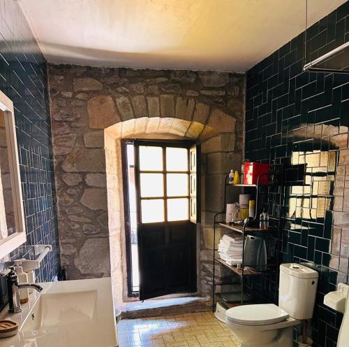 a bathroom with a toilet and a stone wall at Goikitxe Etxea in Goizueta