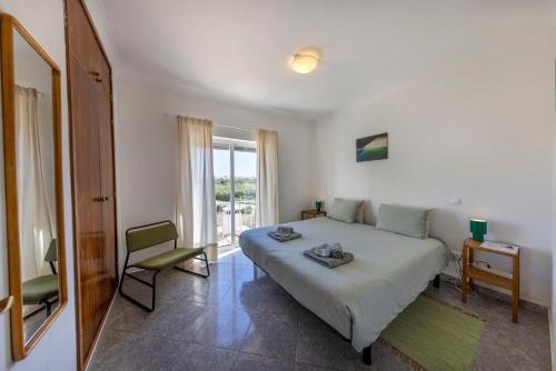 a bedroom with a bed and a chair and a window at Local Guesthouse in Sagres