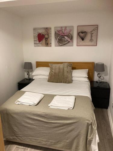 a bedroom with a large bed with three pictures on the wall at Gallowgate Square Apartments in Largs