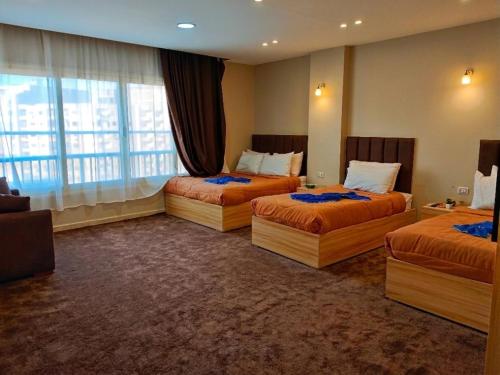 a hotel room with three beds and a window at Horus Pyramids Horizon INN in Cairo