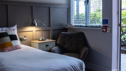 a bedroom with a bed and a chair and a lamp at The Crown & Horns in Newbury
