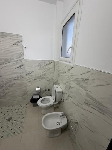 a bathroom with a toilet and a window at Villa Kokoneshi in Divjakë