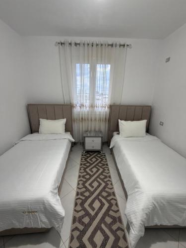 two twin beds in a room with a window at Villa Kokoneshi in Divjakë