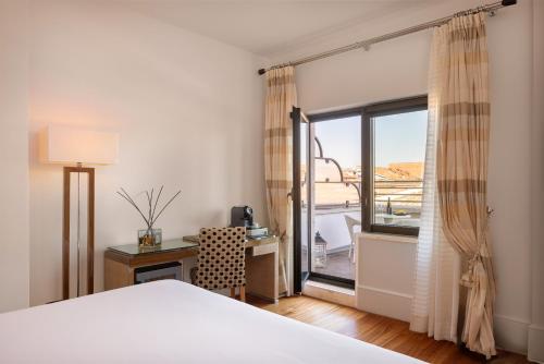a bedroom with a bed and a desk and a window at UNA Hotels Decò Roma in Rome