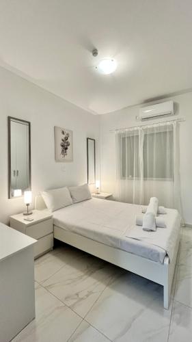 a white bedroom with a large bed and two tables at Christiana's House in Artemida