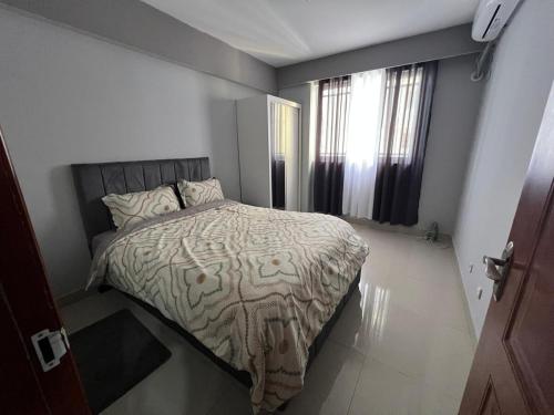 a bedroom with a bed and two windows at Magnólia Home in Muceque Baia