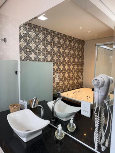 a bathroom with a hair dryer and a bath tub at Pousada Contos de Minas in Mariana