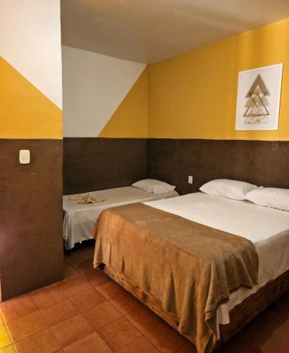 two beds in a room with yellow and white walls at Pousada SolMaris in João Pessoa