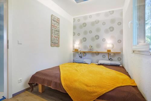 a bedroom with a bed with a yellow blanket at Nordisch Kühl in Mariendorf