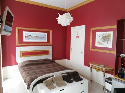 a bedroom with a bed with red walls and a chandelier at Legendary Bay - Suíte Temática in Seixal