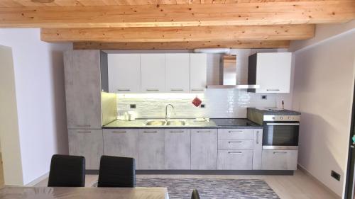a kitchen with white cabinets and a wooden ceiling at La dimora nelle Rue in Civitella Roveto