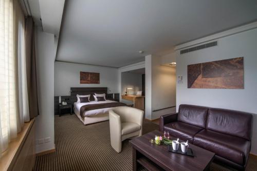 a hotel room with a bed and a couch at Crowne Plaza Zürich by IHG in Zurich