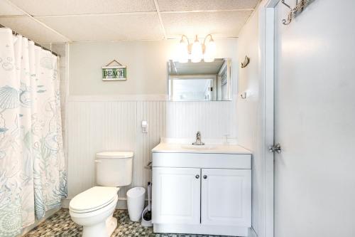 a bathroom with a toilet and a sink and a mirror at Beachfront Wildwood Crest Condo w/ Pool Access! in Wildwood Crest