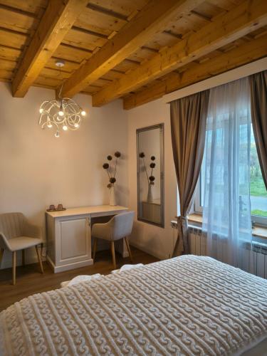 a bedroom with a bed and a desk and a window at Casa Via Viscri in Buneşti