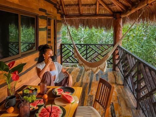 a woman sitting at a table on a porch at Treehouse Tulum H2Ojos in Tulum