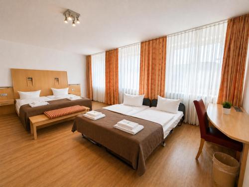 a hotel room with two beds and a desk at Hotel Wania in Hamburg