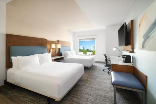 a hotel room with two beds and a desk at EVEN Hotel Alpharetta - Avalon Area by IHG in Alpharetta