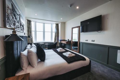 a bedroom with a large bed with a television on the wall at The Royal Bar & Shaker in Morecambe