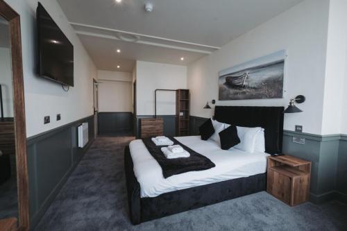 a bedroom with a large bed and a television at The Royal Bar & Shaker in Morecambe