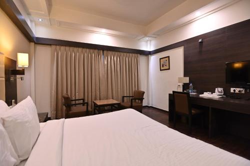 a hotel room with a bed and a desk with a computer at Orient Resorts in Kānpur