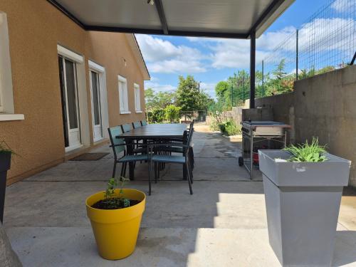 a patio with a table and chairs and potted plants at Lake Villa Castéra-Verduzan in Castéra-Verduzan