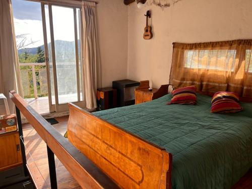 a bedroom with a bed with a green comforter and pillows at Hospedaje San Luis Sierras in Juana Koslay 
