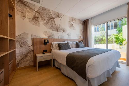 a bedroom with a bed and a wall with drawings on it at Neptuno Aparthotel in Calella