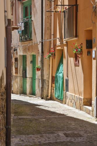an alley with green doors and flowers in an alley at Casa Vacanza Nì Rosa in Cefalù
