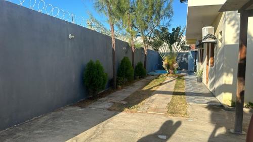 a side walk next to a blue wall with a tree at Pousada Recanto do Marinheiro in Aracati