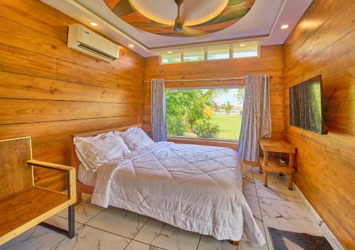 a bedroom with wooden walls and a bed with a window at JC Den Private Villas Kochi by VOYE HOMES in Cochin