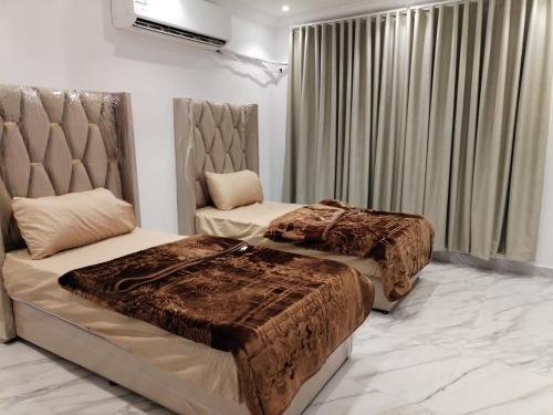 a bedroom with two beds and a window with curtains at غرف عزاب وشقق عوايل in Riyadh