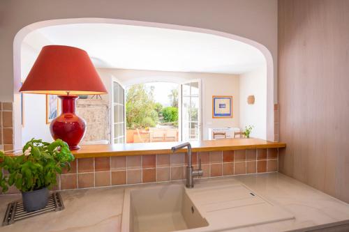 a kitchen sink with a red lamp and a window at Port-Grimaud - La Maisonnette - sur plage et front de mer in Grimaud