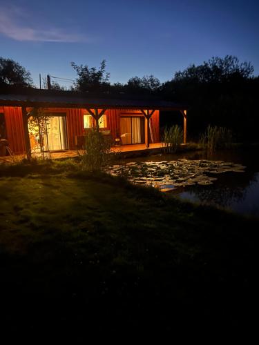 a house with a pond in front of it at night at Chalet in Fleury-sur-Loire