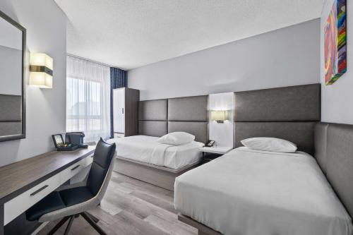 a hotel room with two beds and a desk at Travelodge by Wyndham Montreal Centre in Montreal