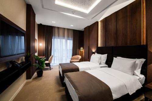 a hotel room with two beds and a television at Premium Hotel, Novi Sad in Novi Sad