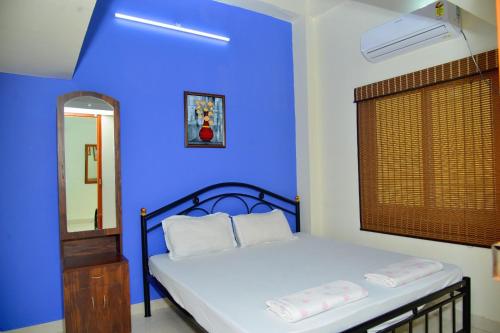 a blue bedroom with a bed with a blue wall at Arun Lodge and Cottage Near Thiruchendur in Korkai