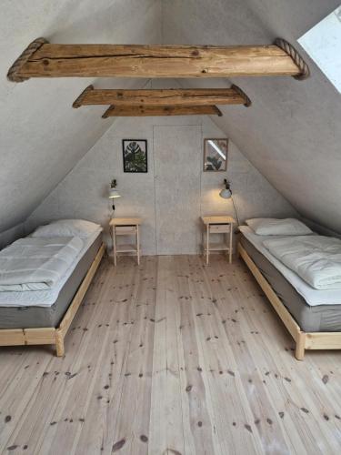 two beds in a attic room with wooden floors at Hyttan in Åkirkeby