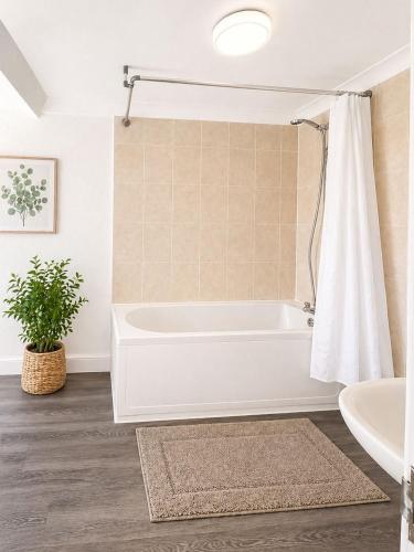 a white bath tub in a bathroom with a plant at Marine Parade - Beach Apartment in Southtown