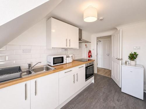 a kitchen with white cabinets and a sink at Marine Parade - Beach Apartment in Southtown
