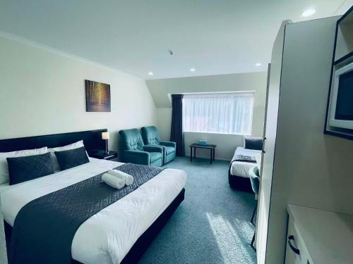 a hotel room with a bed and a chair at Legends Motel in Palmerston North