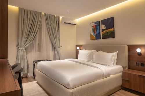 a bedroom with a large white bed and curtains at Seashell Suites in Abuja