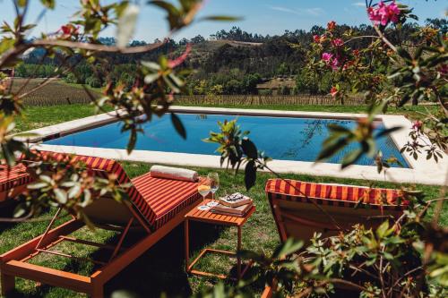 a swimming pool with two chairs and a table next to it at Taboadella Casa Villae 1255 - Relais & Châteaux in Penalva do Castelo