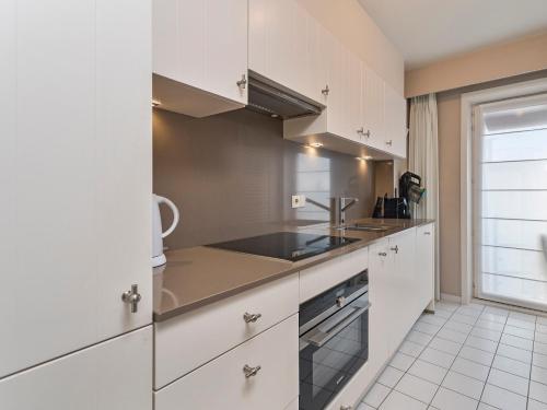 a kitchen with white cabinets and a sink at Beaufort 0401 in Wenduine