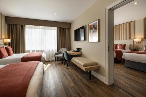 a hotel room with two beds and a desk at Da Vinci's Hotel in Derry Londonderry