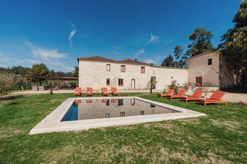 a yard with a pool with chairs and a house at Taboadella Casa Villae 1255 - Relais & Châteaux in Penalva do Castelo